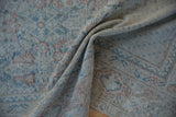 Distressed Mahal carpet texture showing geometric vinery in dusty teal and brick red.
