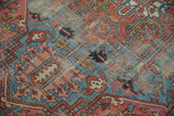 Antique Heriz carpet detail: geometric vinery, palmettes, wear in blue and red tones.