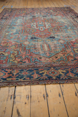 Antique Heriz carpet: geometric vinery, palmettes, dusty cherry, sky blue, and aged pile.