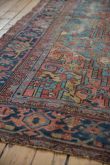 Geometric patterns and vinery on the antique Heriz rug, showing wear to the foundation.