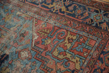Antique Heriz carpet detail, geometric patterns in sky blue, brick red, navy, showing worn pile.