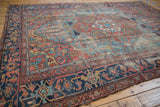 Geometric vinery, palmettes, brick red, and navy blue border on an antique Heriz carpet.