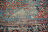 Antique Heriz carpet detail showing wear to foundation and low pile, with blue and red geometric motifs.