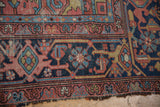 Antique Persian Heriz carpet corner, revealing wear to foundation and geometric patterns in navy, red, and sky blue.
