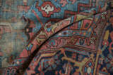 Hand-knotted antique Heriz rug, geometric blue and red pattern with visible foundation wear.