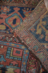 Folded antique Heriz rug revealing worn geometric pile, navy blue, and detailed foundation weave.