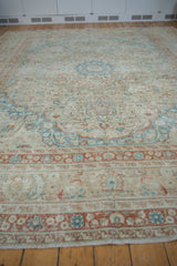 Distressed texture featuring ivory, dusty blue, terracotta floral patterns on a vintage Meshed rug.