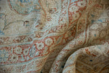 Distressed texture of a vintage Persian Meshed rug, featuring ivory, dusty blue, and terracotta tones.