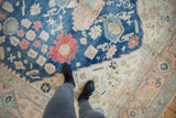 Distressed vintage Oushak carpet's indigo blue field with red and rose palmettes, and ivory border.
