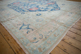 Vintage Distressed Oushak rug corner: pale dusty rose field, blue border, visible wear.