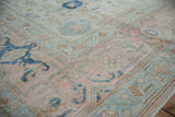 Distressed Oushak rug, pale dusty rose and indigo blue floral motifs with visible wear.
