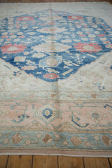 Vintage distressed Oushak carpet showing soft pale rose and faded blue geometric borders.