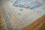 Distressed Vintage Oushak carpet corner, pale dusty rose, indigo blue borders, visible wear.