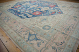 Distressed vintage Oushak rug border showcases soft rose, indigo, and ivory floral designs.