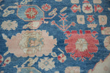 Close-up: hand-knotted Oushak distressed pile, indigo, pale rose, and cherry red floral palmettes.