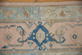 Distressed Oushak rug detail with indigo palmette, pale dusty rose field, and visible wear.