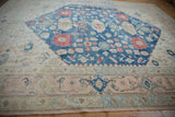 Distressed Oushak rug border showing pale dusty rose, blue motifs, and visible wear.