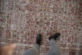 Distressed vintage Khorassan carpet showing worn ivory foundation and intricate red floral vinery.