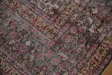 Distressed Persian Khorassan rug detail: scrolling vinery, cochineal red, charcoal, and ivory wear.