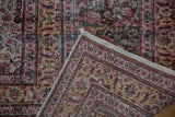 Distressed Khorassan rug corner, highlighting worn scrolling vinery, blush, and raspberry reds.