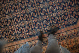 Detailed view of the repeating Herati fish motif in dusty blush and ivory on a fine navy blue Lilihan carpet.