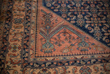 Detailed corner view of a Persian Lilihan carpet with its dusty blush spandrel and navy blue field.