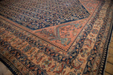 A dusty blush corner spandrel and navy blue Herati field on a vintage Persian Lilihan carpet.