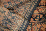 Worn texture and hand-knotted detail of a vintage Lilihan carpet's intricate floral border.