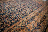 Angled view of the vintage Lilihan carpet's low pile, navy Herati design, and detailed blush border.