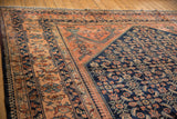Angled corner view of a vintage Lilihan carpet showing the navy Herati field and blush floral border.