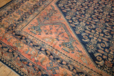 Corner detail of a vintage Lilihan carpet contrasting the navy blue Herati field and blush spandrel.