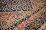 Textured low pile at the corner of a vintage Lilihan carpet with a navy Herati field and blush border.
