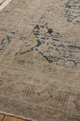 Faded ivory and dusty navy floral motifs with visible foundation on this distressed Khotan rug.