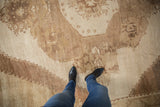Distressed Oushak rug, showing stepped corner spandrel with muted ivory and coffee brown tones.
