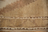 Vintage distressed Oushak carpet with stepped geometric border patterns in ivory, beige, and coffee brown.