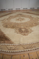 Stepped geometric border detail of a distressed Oushak rug in antique ivory and coffee brown.