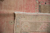 Vintage Oushak rug's distressed blush pile, hand-knotted foundation, and antique ivory fringe.