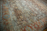 Distressed Mahal carpet's worn pile, revealing muted terra cotta, blue, and platinum patterns.