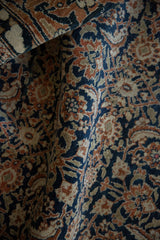 Folded vintage Tabriz carpet with Herati design in deep navy, rust, and warm beige.