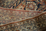Vintage Tabriz carpet fold revealing hand-knotted foundation with rust and navy woven edge.