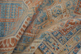 Distressed Karaja rug texture reveals worn geometric motifs in sky blue, pale red, and ivory.