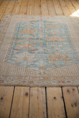 Distressed Afshar square rug close-up, faded blue and gold floral patterns, visible foundation.