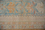 Distressed Afshar rug lower border with geometric patterns in powder blue, sand, and pale gold.