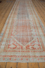 Long perspective view of a distressed Mahal runner's rust and blue diamond boteh field.
