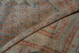 Close-up of the distressed Persian rug's low pile, revealing the hand-knotted weave and foundation.