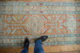 Distressed Heriz runner, showcasing geometric floral pinwheel motifs in pale terra cotta and blue.