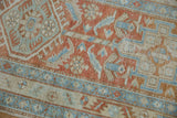 Distressed vintage Heriz rug's faded geometric floral design in pale terra cotta and powder blue.