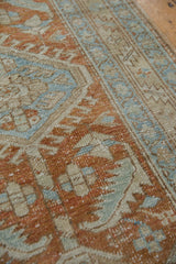 Textured distressed pile of vintage Heriz runner with geometric patterns in terra cotta, pale blue.