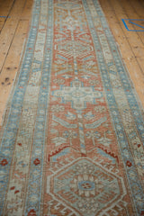 Distressed vintage Heriz runner with faded terra cotta and pale blue geometric floral pinwheel patterns.