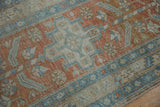 Distressed vintage Heriz rug close-up: geometric floral pinwheel, pale terra cotta, powder blue.